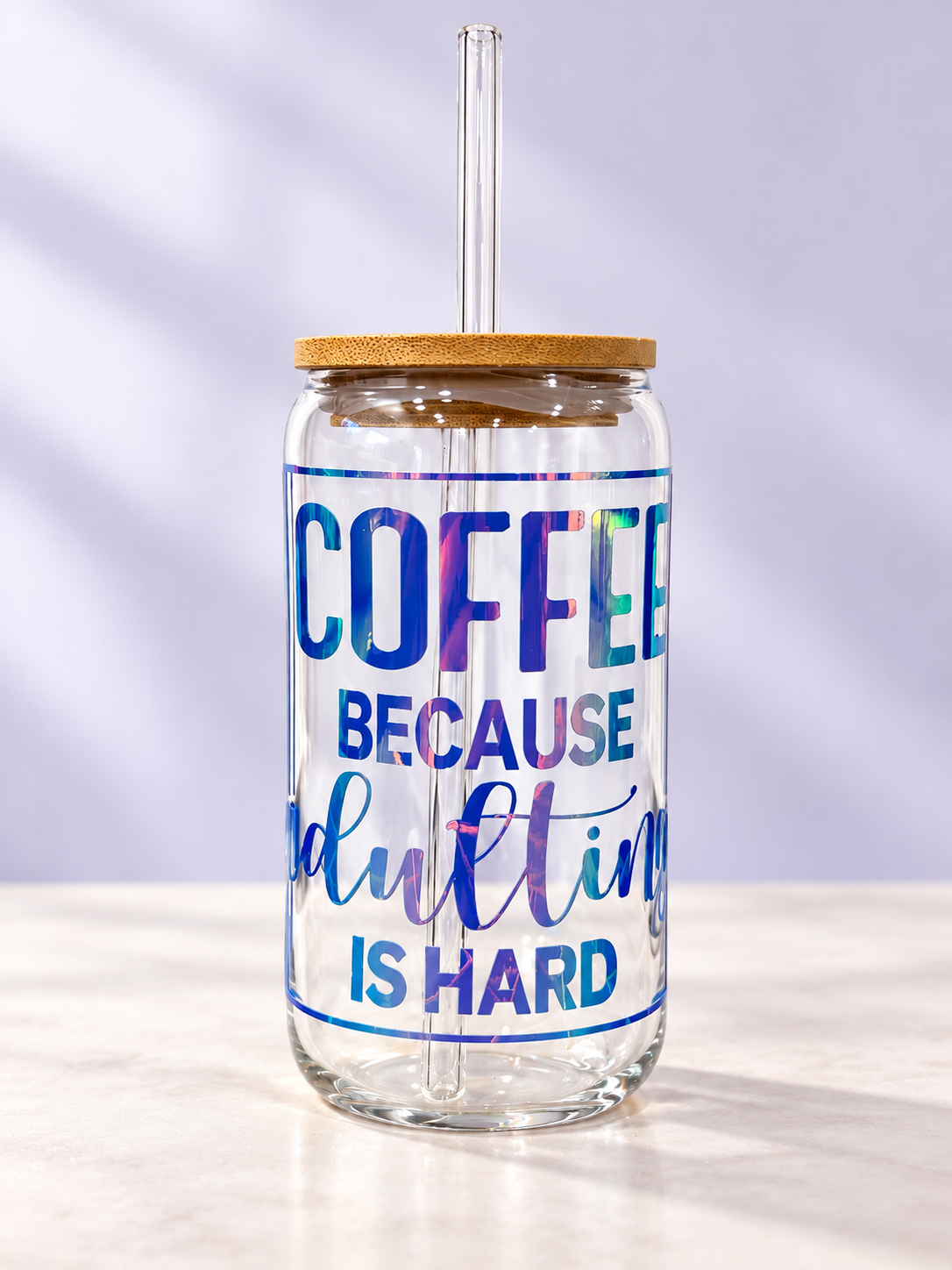 16oz clear glass coffee tumbler featuring holographic Coffee Because Adulting Is Hard lettering with bamboo lid and reusable glass straw.