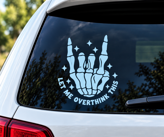 Light-colored Let Me Overthink This vinyl decal featuring a skeleton hand making a rock-on gesture and sparkle accents on a car’s rear window.