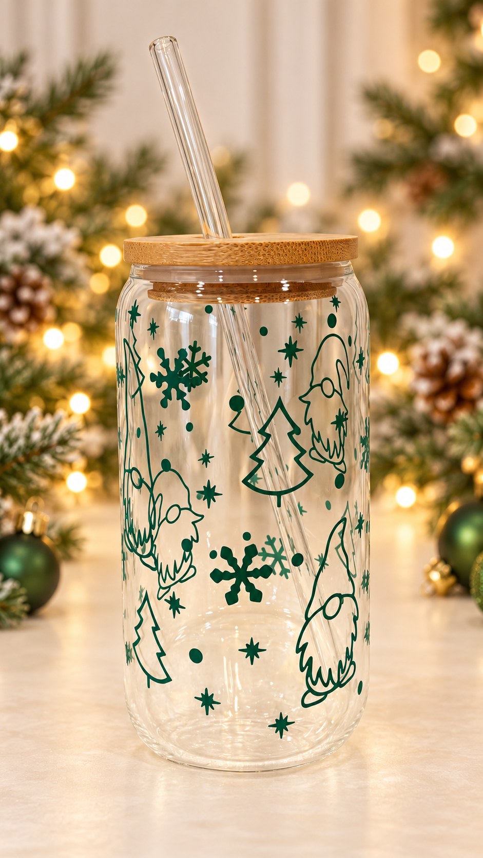 Clear glass tumbler decorated with green Christmas gnomes, trees, snowflakes, and stars, topped with a bamboo lid and clear glass straw.