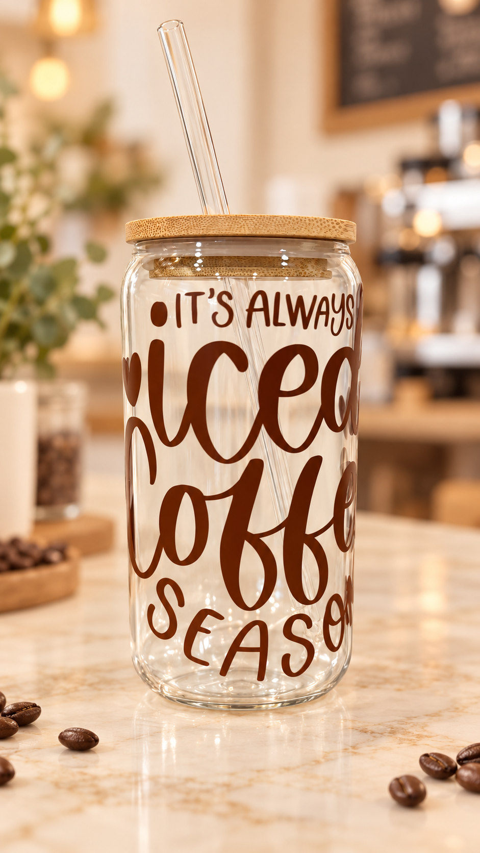 Clear glass tumbler with brown “It’s Always Iced Coffee Season” lettering and hearts, a bamboo lid, and a clear glass straw.